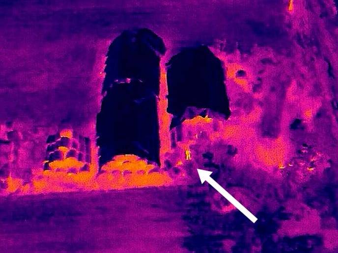 Obraz kamery termowizyjnej drona. Strzałką wskazano zaginionego pana Mariana